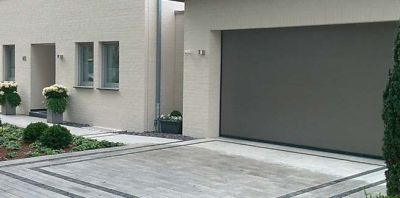 Garagentor mit Zufahrt neben einem Wohnhaus